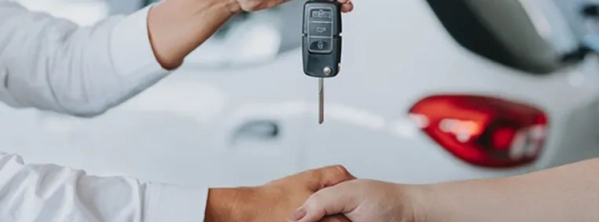 dos manos dandose la mano y la llave de un coche