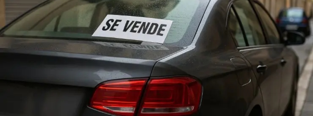 la parte trasera de un coche y en la luna tiene un cartel de "se vende"